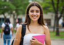 Young Smiling Woman with Pink Notebook Outdoors on Campus