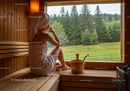 Woman Relaxing in Wooden Sauna with Forest View During Wellness Retreat