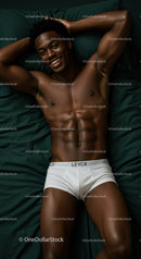 Smiling man relaxing in white underwear on dark bed