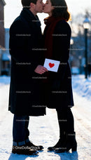 Couple sharing a tender kiss with Valentine card outdoors