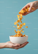 Hand Pouring Crunchy Cornflakes into White Bowl
