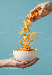 Hand Pouring Crunchy Cornflakes into White Bowl