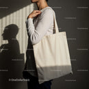 Person carrying blank canvas tote bag in soft light