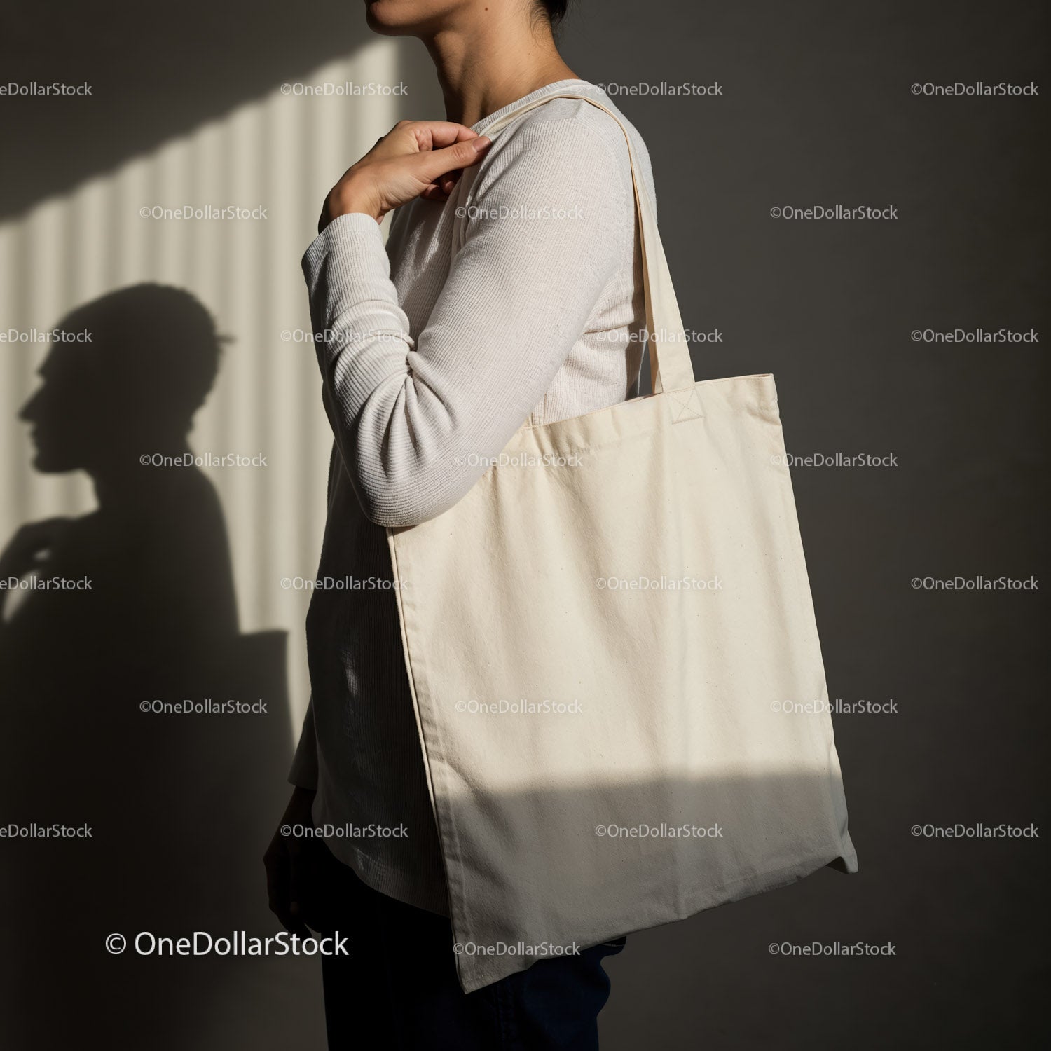 Person carrying blank canvas tote bag in soft light