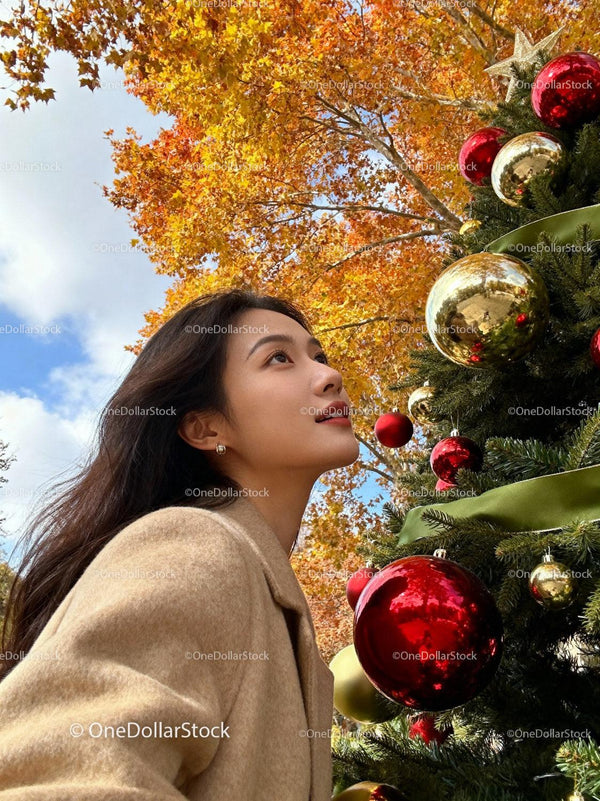 Young woman admiring decorated Christmas tree outdoors