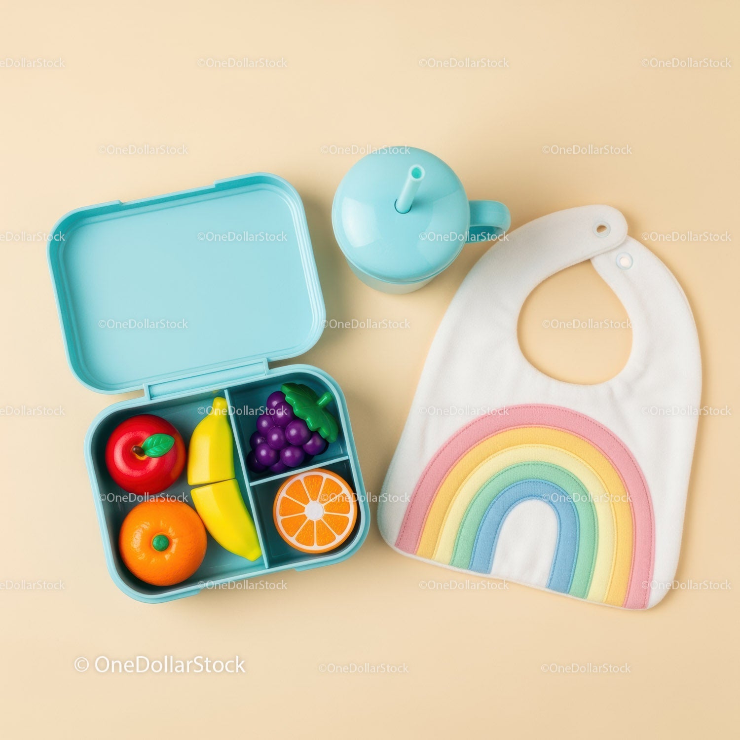 Colorful baby lunchbox with toy fruit and pastel bib