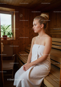 Relaxing Woman Sitting in Sauna with Towel in Wooden Interior