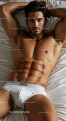 Fit young man relaxing on bed in white briefs