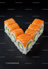 Salmon sushi rolls arranged in heart shape on black slate