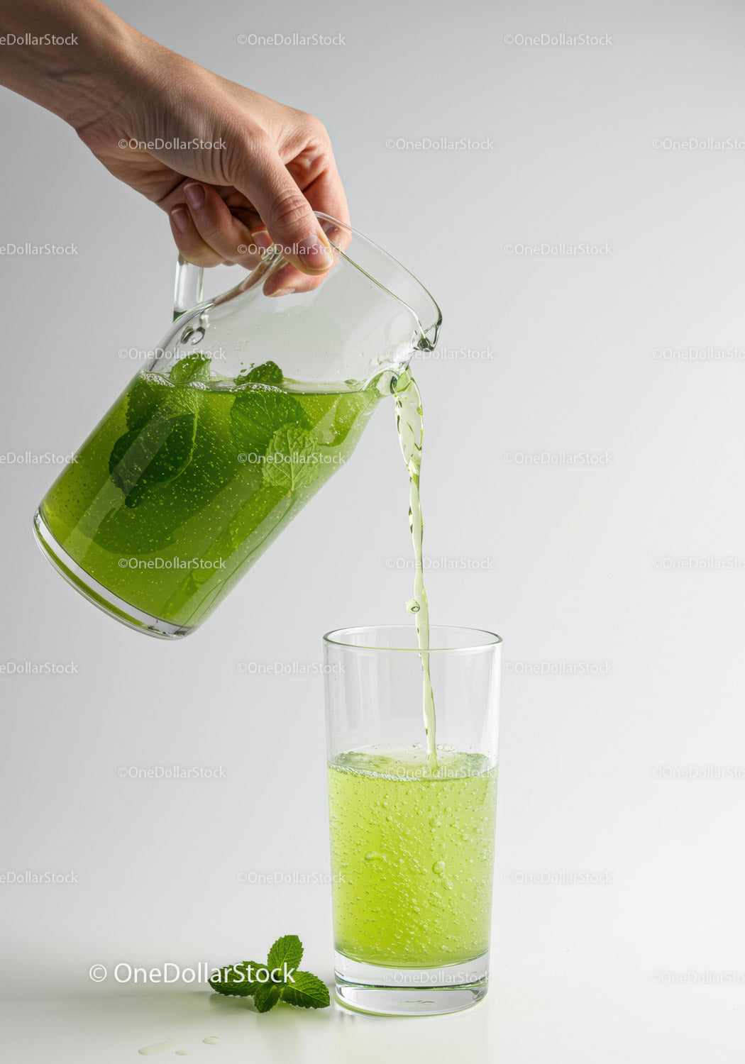 Hand pouring refreshing mint lemonade into glass