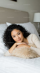 Calm young woman relaxing on bed with soft pillow