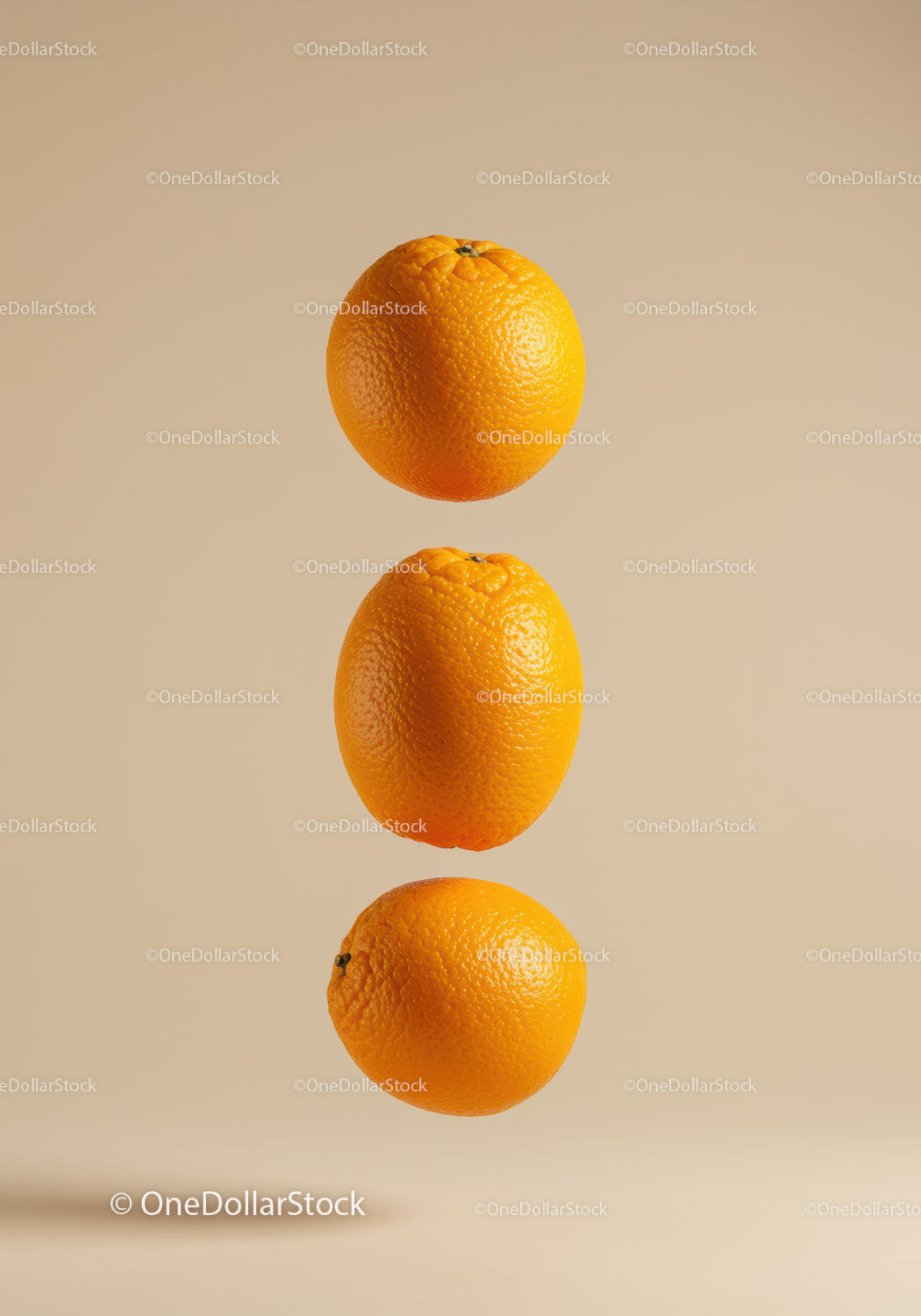 Three floating fresh oranges on beige background