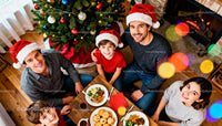 Family enjoying festive meal by Christmas tree and fireplace