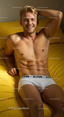Smiling young man relaxing on yellow bed in white underwear