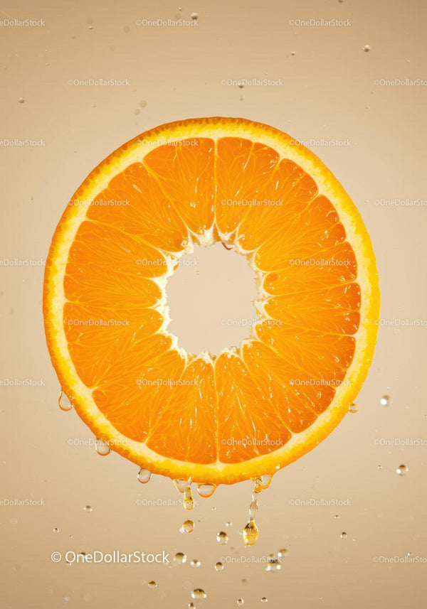 Fresh orange slice dripping juice in soft light