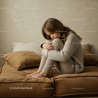 Quiet young girl hugging knees on cozy sofa
