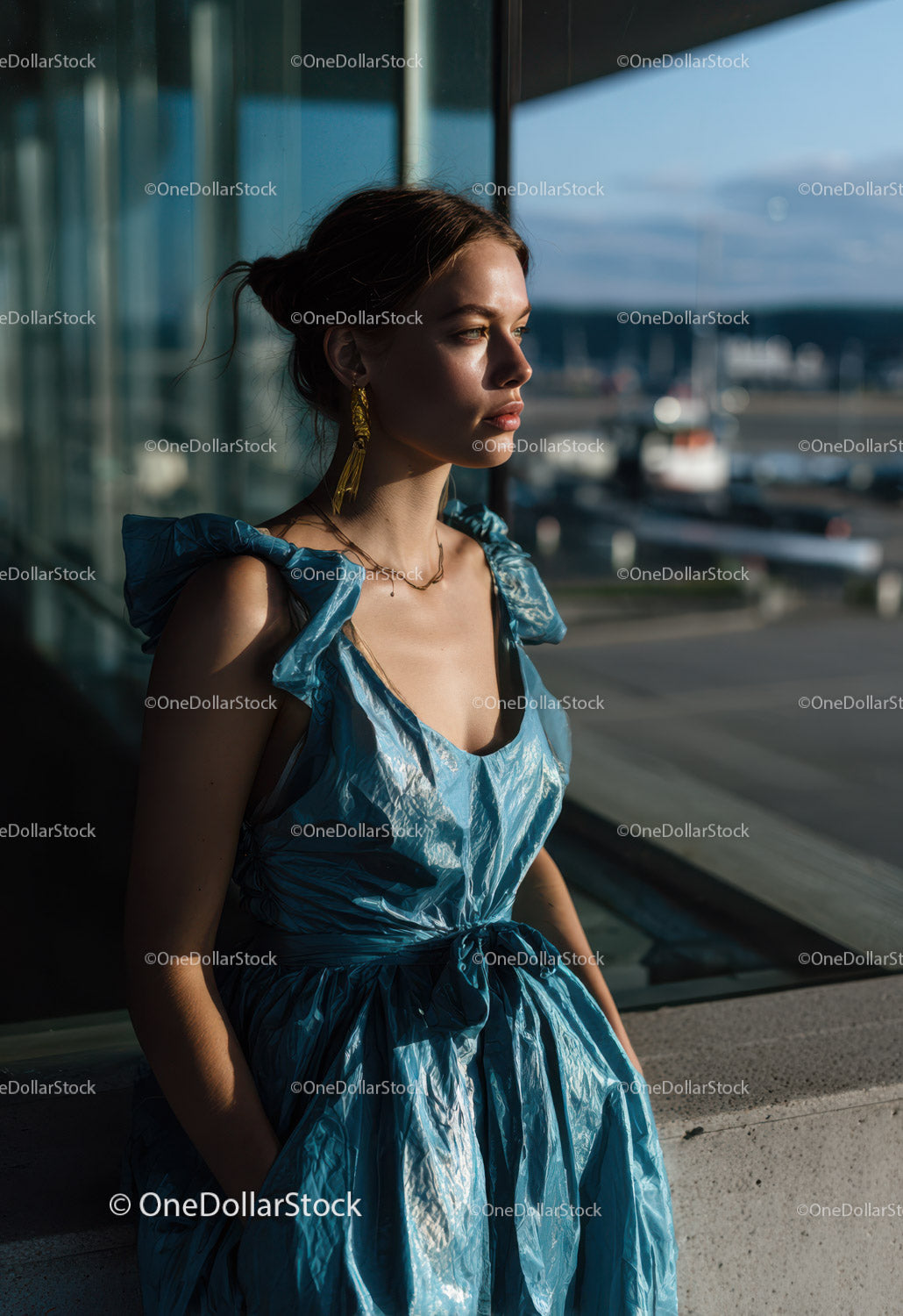 Young Woman in Blue Metallic Dress Near Large Glass Window at Airport