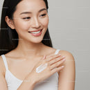 Portrait of a Smiling Woman Applying Lotion with Flawless Skin