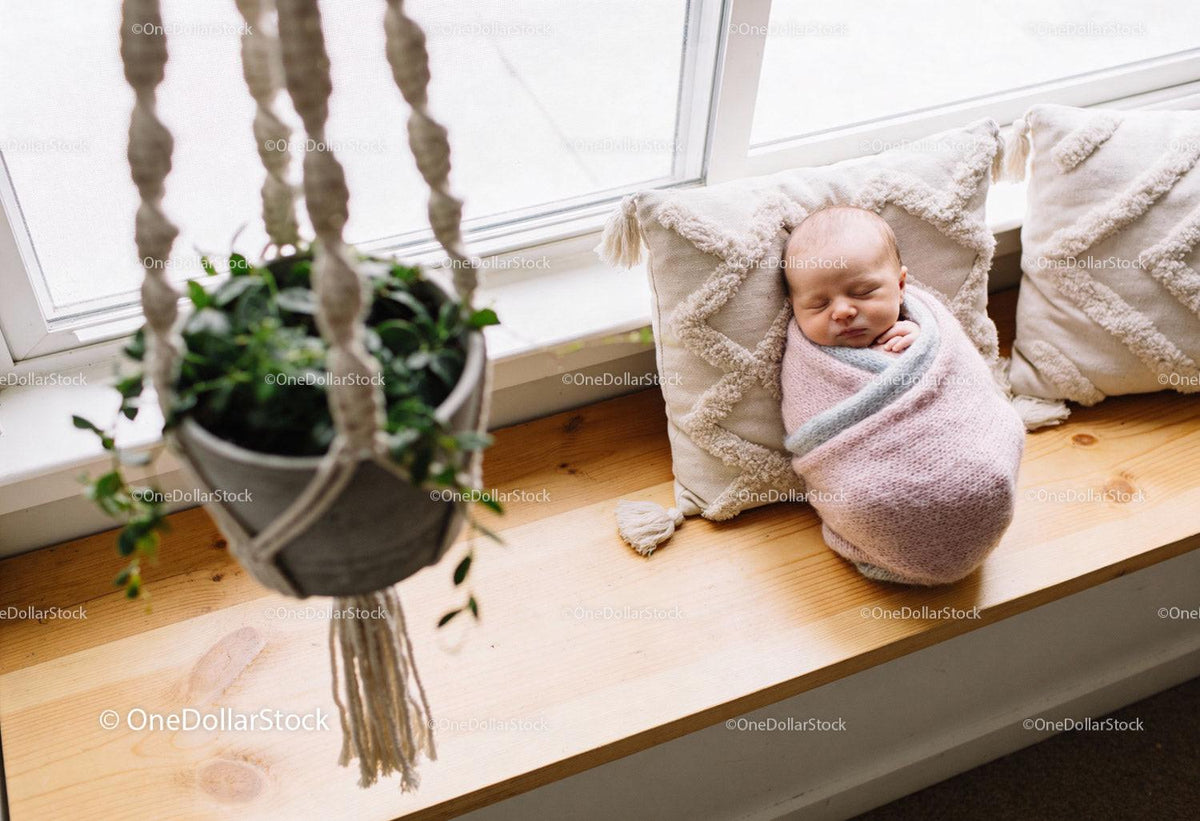 Newborn baby peacefully sleeping on cozy window bench