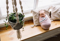 Newborn baby peacefully sleeping on cozy window bench