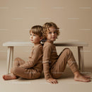 Two children sitting back to back under wooden bench
