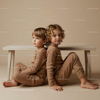 Two children sitting back to back under wooden bench