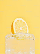 Refreshing lemon slice on ice cube with yellow background