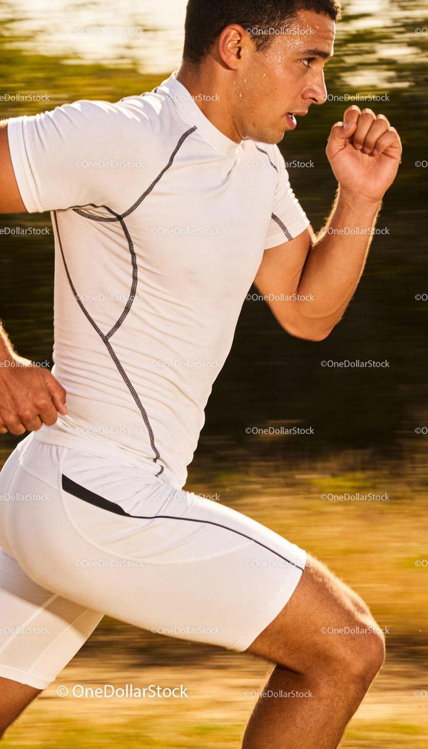 Focused male athlete sprinting outdoors in white sportswear
