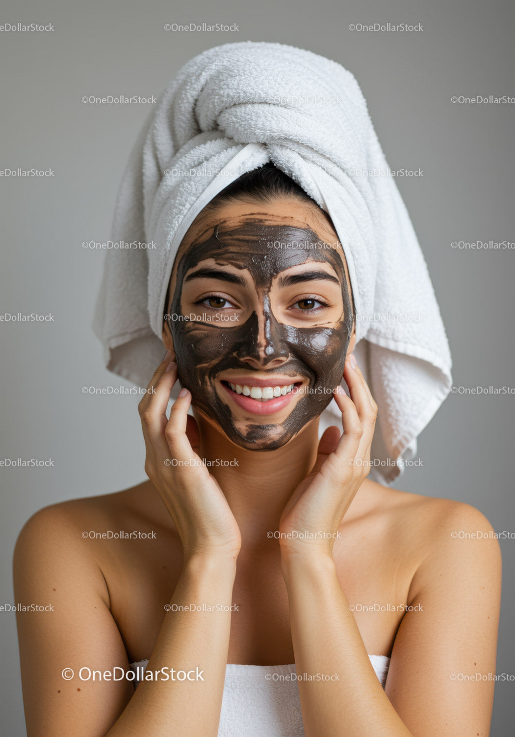 Kobieta nakładająca maseczkę na twarz z głową owiniętą ręcznikiem w salonie spa