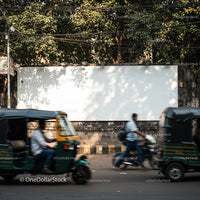 Busy urban street with passing auto rickshaws and pedestrians