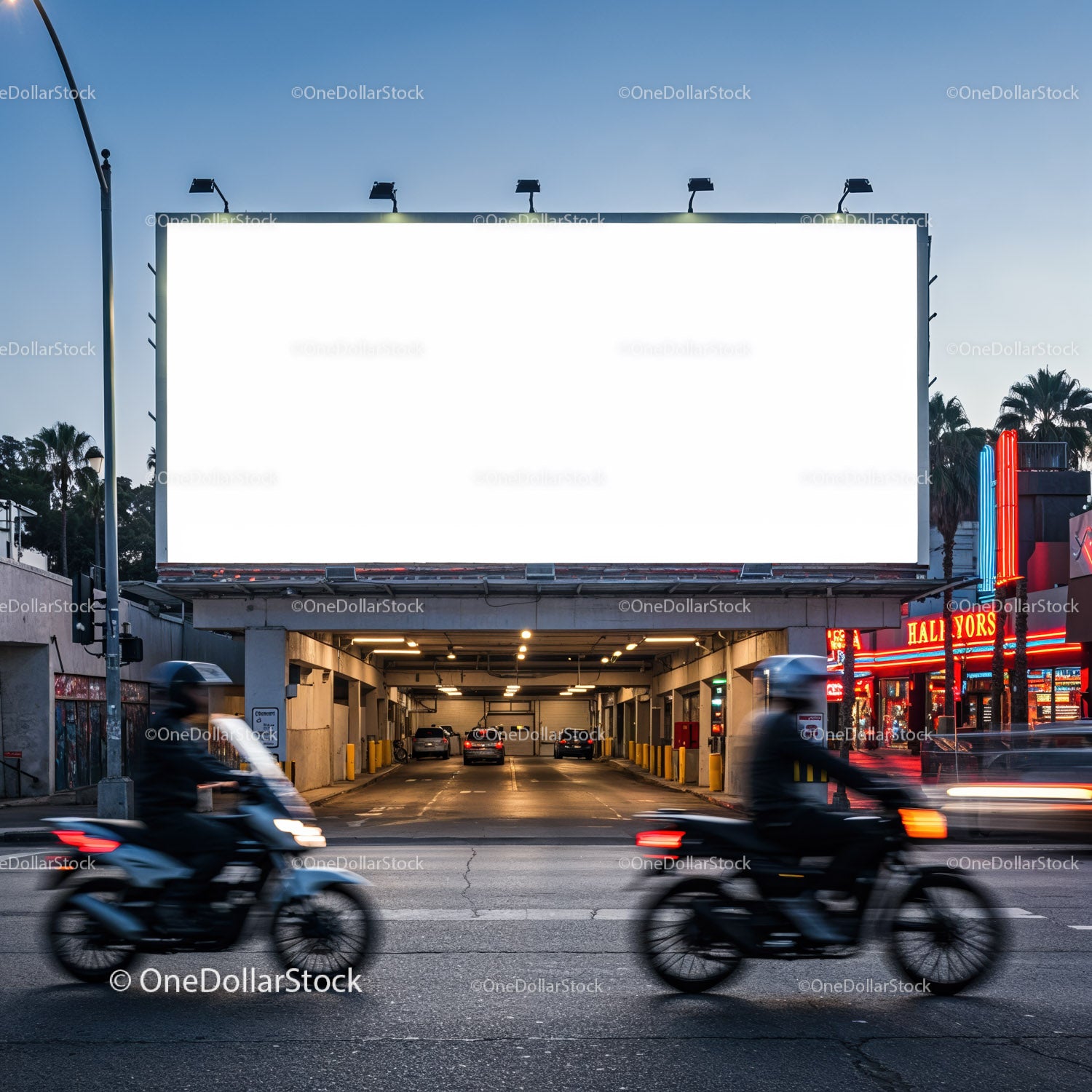 Empty illuminated billboard over city parking garage at dusk