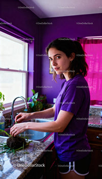 Young woman cleaning plant roots in vibrant kitchen