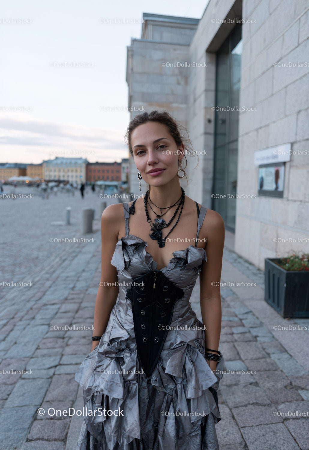 Stylowa młoda kobieta w falbaniastej sukience z biżuterią na miejskiej ulicy