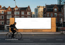 Cyclist passing by large urban blank billboard in daylight