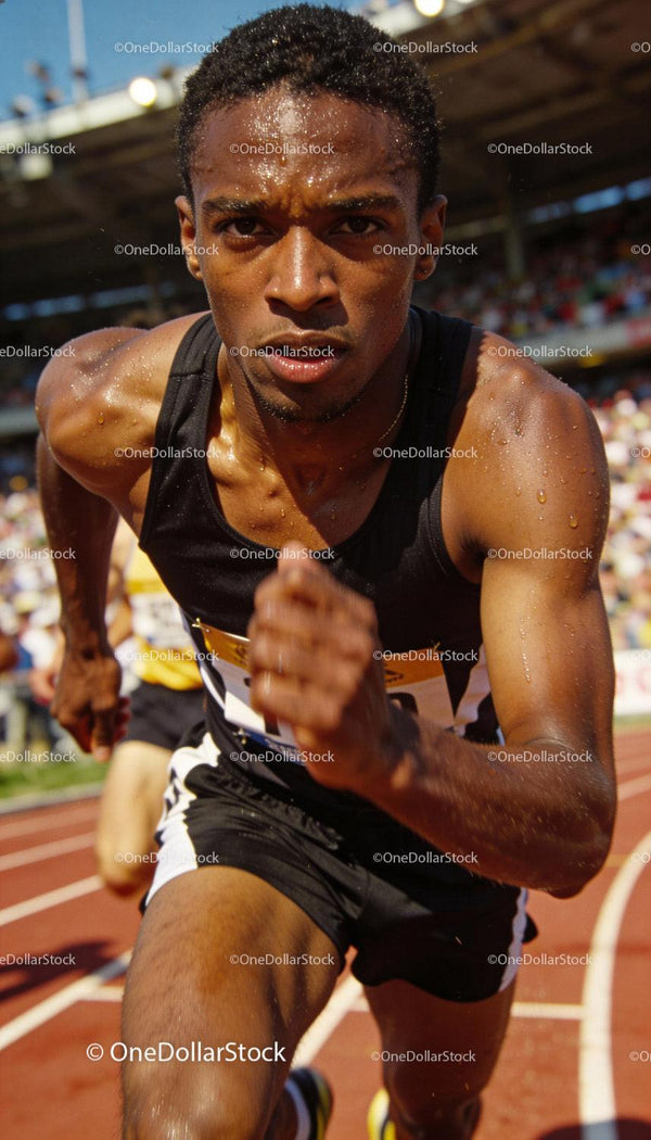 Focused male sprinter competing on outdoor track stadium