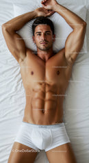 Fit young man relaxing in white briefs on bed