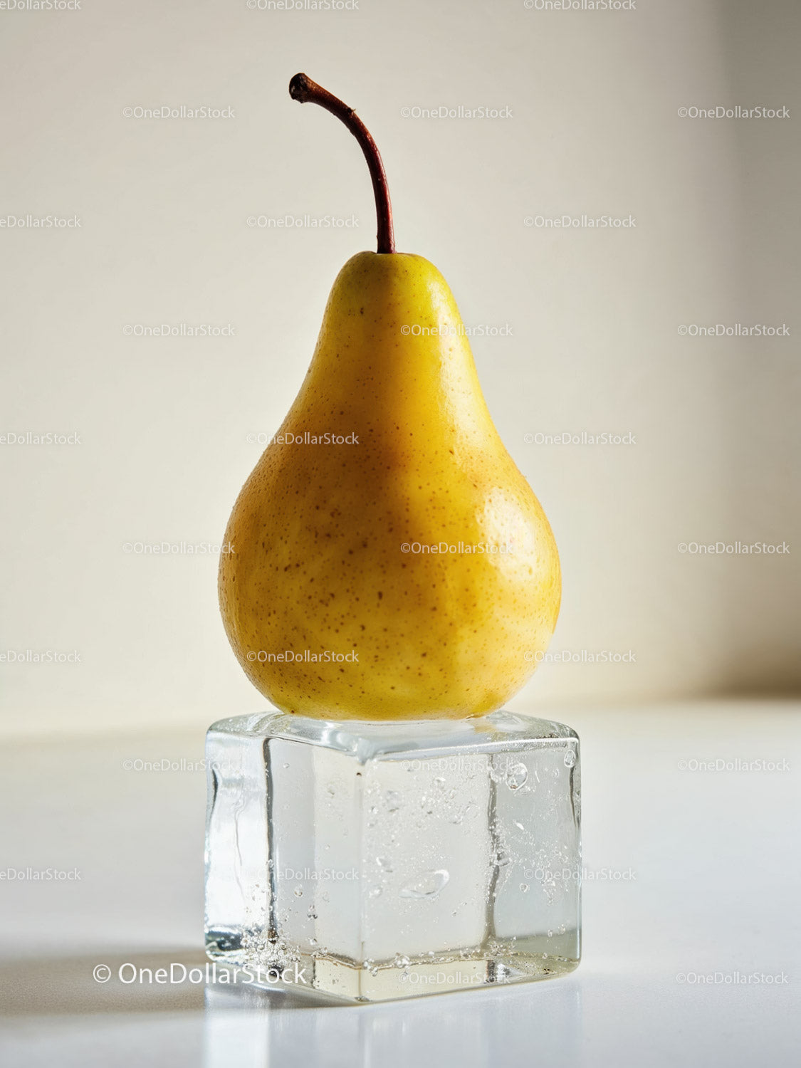 Fresh yellow pear balanced on large melting ice cube