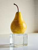 Fresh yellow pear balanced on large melting ice cube