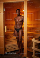 Young Man with Chiseled Abs Standing in Sauna Interior