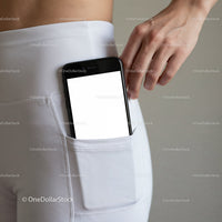 Smartphone tucked into white leggings pocket