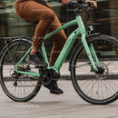 Person Riding Modern Green Electric Bike in Urban Setting