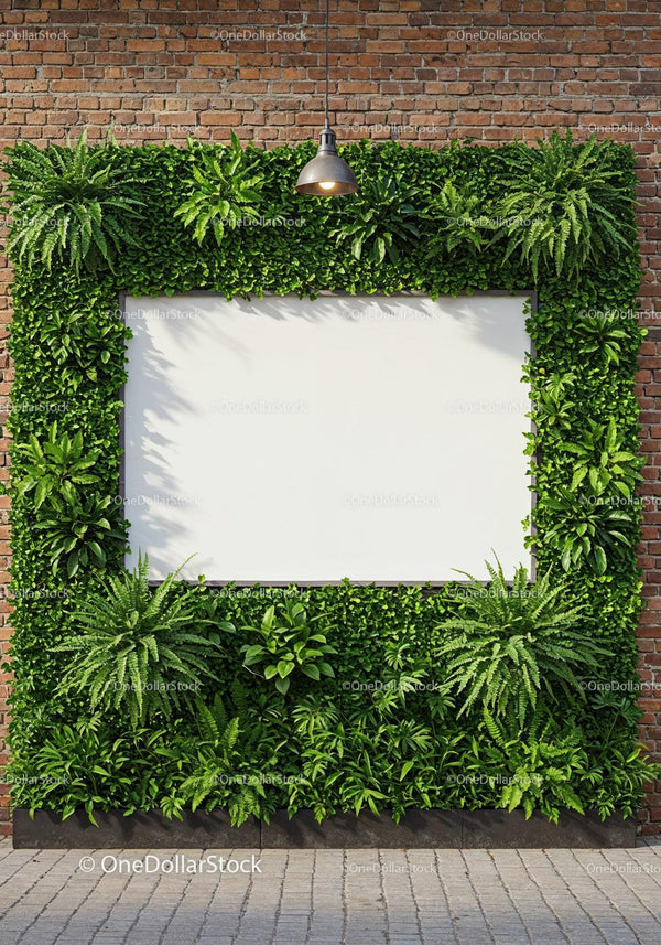 Blank white billboard framed with lush green plants on brick wall JPG Mockup Image