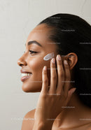 Young Woman Applying Skincare Cream on Cheek for Healthy Skin