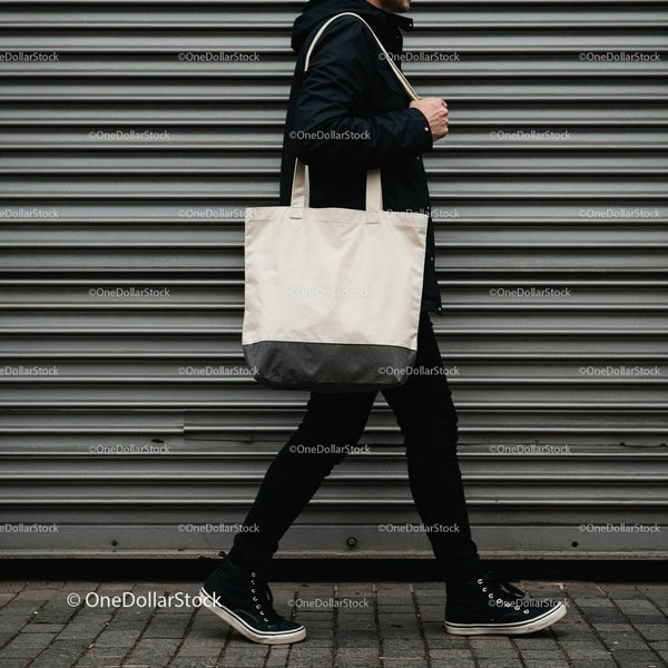 Person walking with white canvas tote bag on city street JPG Mockup Image