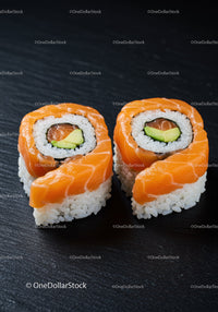 Fresh salmon sushi rolls with avocado on black slate
