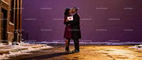 Couple sharing a kiss holding a heart card at night