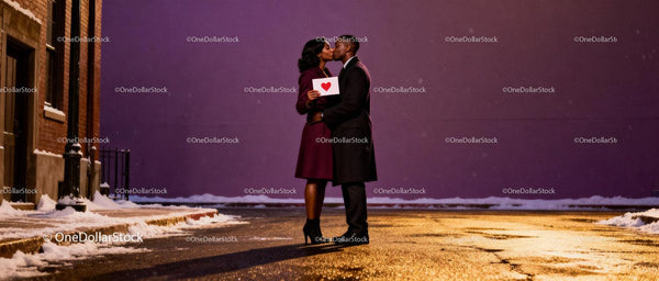 Couple sharing a kiss holding a heart card at night