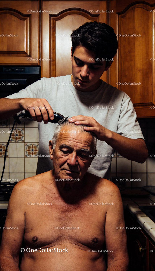 Young man giving an elderly man a haircut at home