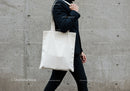 Man carrying blank white tote bag walking outdoors