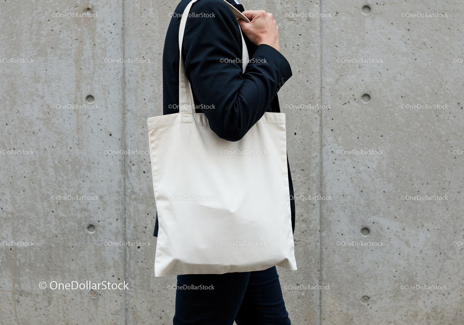 Person Carrying Blank Canvas Tote Bag Against Concrete Wall